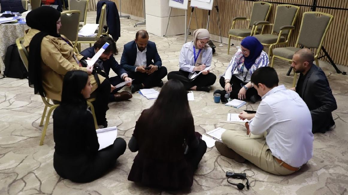 A group of youth gather in a circle on the floor at a Youth, Peace and Security workshop in Amman, Jordan