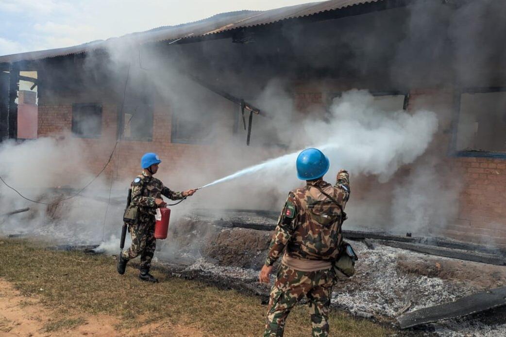 Deux casques bleus éteignent un incendie dans un bâtiment.